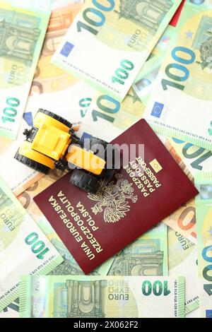 Roter polnischer Pass und gelber Traktor auf Euro-Geldscheinen aus nächster Nähe Stockfoto