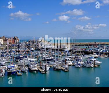 Ramsgate Royal Harbour voller verschiedener Boote und Yachten, unter einem blauen Himmel mit flauschigen weißen Wolken. Stockfoto