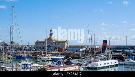 Ramsgate Royal Harbour voller verschiedener Boote und Yachten, unter einem blauen Himmel mit flauschigen weißen Wolken. Uhrengebäude im Hintergrund. Stockfoto