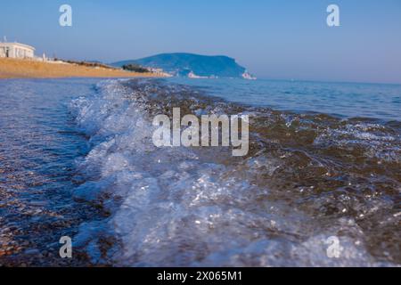 Wunderschönes ruhiges Meer an einem sonnigen Tag. Meereslicht-Surf-Aufnahme aus nächster Nähe. Eine kleine Welle und ein Meeresschaum glitzern in der Sonne. Stockfoto