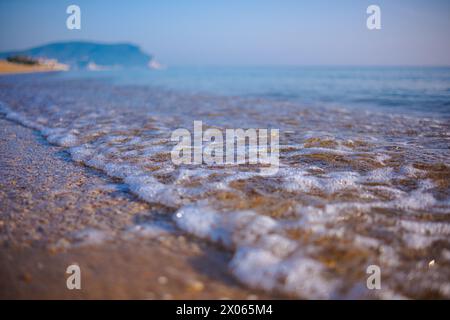 Wunderschönes ruhiges Meer an einem sonnigen Tag. Meereslicht-Surf-Aufnahme aus nächster Nähe. Eine kleine Welle und ein Meeresschaum glitzern in der Sonne. Stockfoto