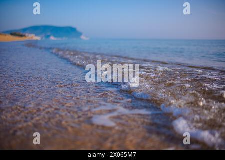 Wunderschönes ruhiges Meer an einem sonnigen Tag. Meereslicht-Surf-Aufnahme aus nächster Nähe. Eine kleine Welle und ein Meeresschaum glitzern in der Sonne. Stockfoto