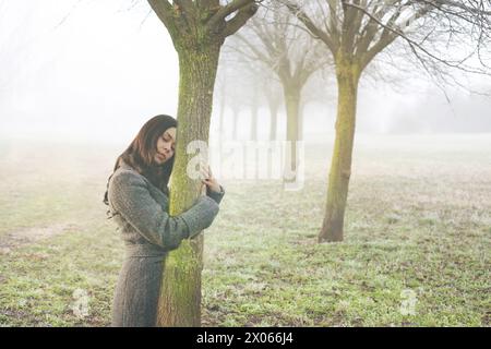 Frau umarmt sanft den Stamm eines Baumes, der das abstrakte Konzept des Lebensbluts symbolisiert Stockfoto