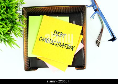 Schuldenkonsolidierung. Dies ist der Prozess, um ein neues Darlehen zur Rückzahlung einer Reihe bestehender Schulden zu erhalten. Der Text steht auf einem gelben Aufkleber Stockfoto