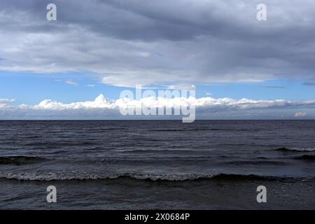 Dunkle kalte Wellen der Ostsee mit einer Schicht weißer Wolken auf der Skyline an einem bewölkten windigen Tag Stockfoto