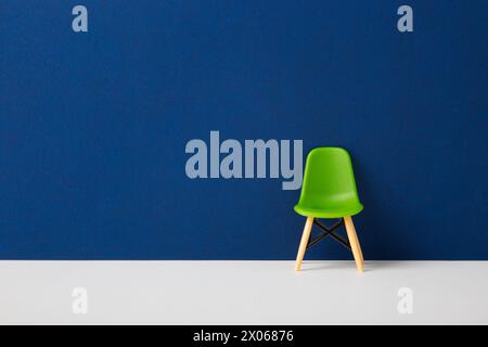Grüner Stuhl an einer blauen Wand. Stockfoto