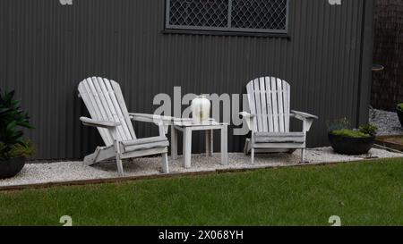 Zwei Adirondack-Stühle mit Tisch und Blick auf den Hinterhof Stockfoto