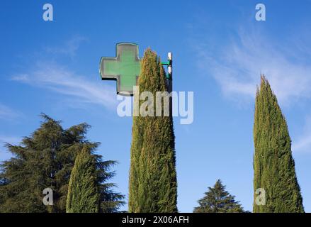 Grüne Kreuzschilder für Apotheken und Zypressenbäume Stockfoto