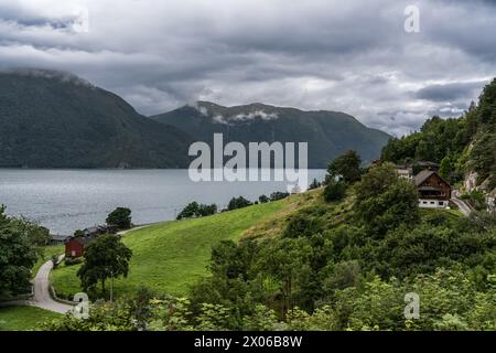 Stürmischer Himmel Über Dem Tingvollfjord In Der Nähe Des Dorfes Ålvundeid. Bewölktes Wetter über dem Fjord mit ländlichen norwegischen Häusern eingebettet in üppiges Grün Stockfoto