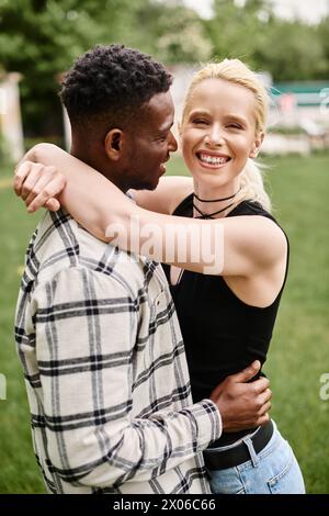 Ein glückliches Paar, bestehend aus einem Afroamerikaner und einer Kaukasierin, die sich liebevoll in einer pulsierenden Parklandschaft umgibt. Stockfoto
