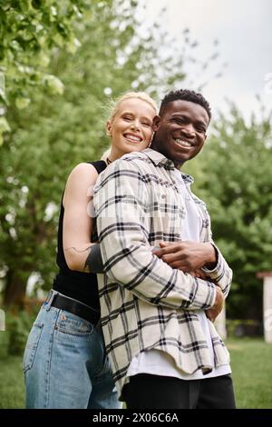 Ein afroamerikanischer Mann und eine kaukasische Frau stehen zusammen im Gras und verbinden sich mit der Natur und miteinander. Stockfoto