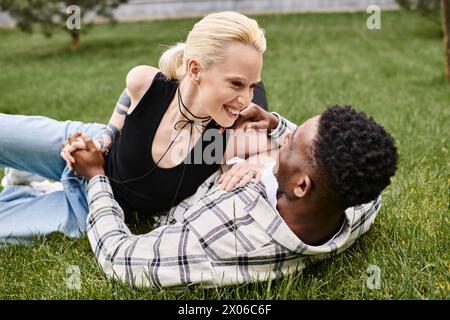 Ein glückliches multikulturelles Paar, ein Afroamerikaner und eine Kaukasierin, die sich gemeinsam im grünen Gras eines Parks entspannen. Stockfoto