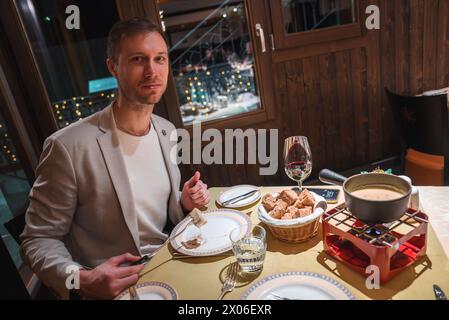 Elegantes Herrenessen in gemütlichem Restaurant mit Fondue und Wein, festlicher Atmosphäre. Stockfoto