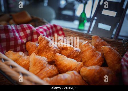 Goldbraune Croissants im Korb mit kariertem Tuch, Essbereich im Zermatt Hotel. Stockfoto