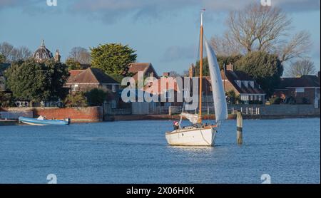 Eine Yacht, die über das obere Ende des Chichester Harbour in Langstone segelt, von der Langstone Bridge aus gesehen, Portsmouth, Hampshire, England, Großbritannien. Stockfoto