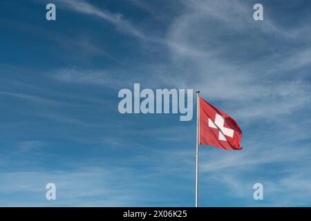 Die Flagge der Schweiz, Europa auf einem Pol, der im Wind winkt. Großer Kopierbereich links. Schweizerkreuz Stockfoto