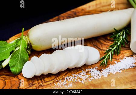 Gartenrettich (Raphanus sativus), zwei Radieschen auf einem Holzbrett, mit Salz geschnitten Stockfoto