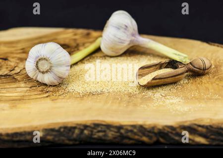 Gemeiner Knoblauch (Allium sativum), Knoblauchgranulat auf einem Holzbrett mit Holzlöffel Stockfoto