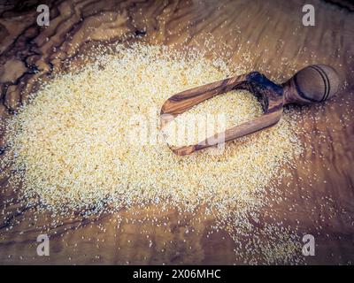 Knoblauch (Allium sativum), Knoblauchgranulat auf einem Teller mit Holzlöffel Stockfoto