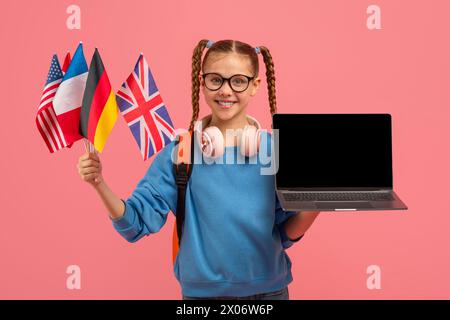 Lächelndes Mädchen mit Fahnen und Laptop in Pink Stockfoto