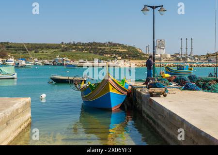 Marsaxlokk, Malta - 23. März 2022: Ein traditionelles Fischerboot namens Luzzu, das in einer Hutbahn im Hafen von Marsaxlokk vor Anker liegt. Stockfoto