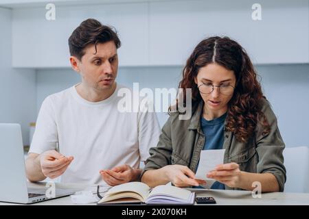 Ein besorgter Mann und eine fokussierte Frau sitzen zusammen, legen mit Belegen und einem Taschenrechner den Haushalt fest und betonen die Bedeutung der Finanzplanung. Ein verheiratetes Paar bildet ein Budget, berücksichtigt Ausgaben für einen Monat. Stockfoto