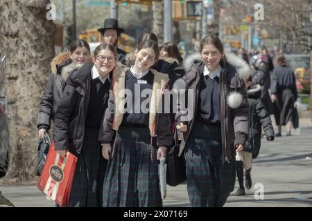 Drei fröhliche chassidische Rirls in passenden Röcken und Schuluniform. Auf der Bedford Avenue in Brooklyn, New York. Stockfoto