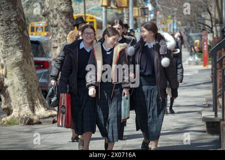 3 fröhliche chassidische Teenager mit passenden Röcken und Schuluniform. Auf der Bedford Avenue in Brooklyn, New York. Stockfoto