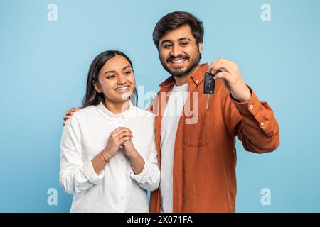 Ein Paar präsentiert neue Autoschlüssel auf blauem Hintergrund Stockfoto