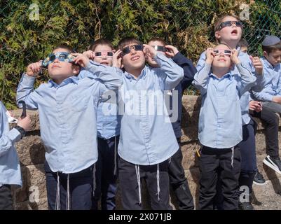 Eine Gruppe orthodoxer jüdischer Jungen beobachten die Sonnenfinsternis 2024 vom Schulhof ihrer Jeschiwa aus. Im Rockland County, New York. Stockfoto