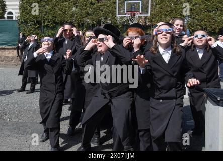 Eine Gruppe orthodoxer jüdischer Jungen beobachten die Sonnenfinsternis von 2024 vom Schulhof ihrer Pfarrschule aus. Im Rockland County, New York. Stockfoto