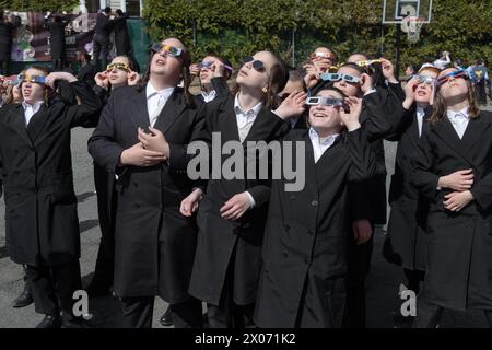 Eine Gruppe orthodoxer jüdischer Jungen beobachten die Sonnenfinsternis von 2024 vom Schulhof ihrer Pfarrschule aus. Im Rockland County, New York. Stockfoto