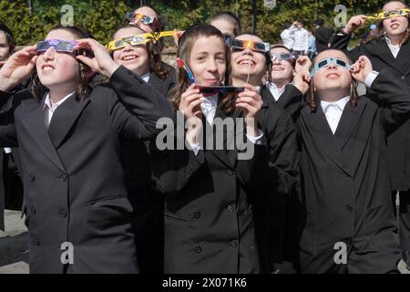 Eine Gruppe orthodoxer jüdischer Jungen beobachten die Sonnenfinsternis von 2024 vom Schulhof ihrer Pfarrschule aus. Im Rockland County, New York. Stockfoto