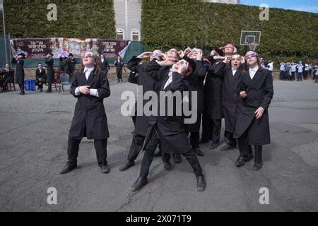 Eine Gruppe orthodoxer jüdischer Studenten beobachtet die Sonnenfinsternis von 2024 auf ihrem Yeshiva-Schulhof im Rockland County, New York. Stockfoto