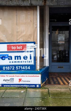 Ein geschlossener und verschlossener heruntergekommener Laden kann im Stadtzentrum von Newquay in Cornwall in Großbritannien vermietet werden. Stockfoto