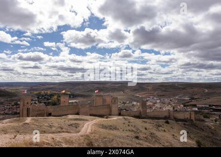 Antike Steinfestung mit Blick auf eine moderne Stadt vor sanften Hügeln und bewölktem Himmel Stockfoto