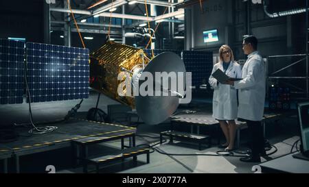 Ingenieur und Techniker, die an der Satellitenkonstruktion arbeiten. Luft- und Raumfahrtbehörde: Ein Team von Wissenschaftlern, das technologische Ausrüstung und Tablet-Computer zur Entwicklung von Raumfahrzeugen für die Weltraumforschung nutzt. Stockfoto