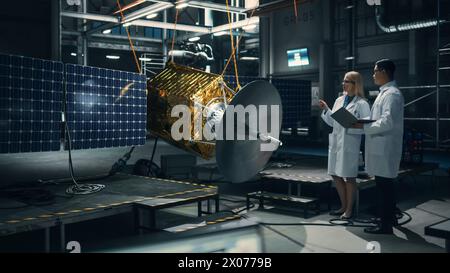 Ingenieur und Techniker, die an der Satellitenkonstruktion arbeiten. Luft- und Raumfahrtbehörde: Ein Team von Wissenschaftlern, das technologische Ausrüstung und Tablet-Computer zur Entwicklung von Raumfahrzeugen für die Weltraumforschung nutzt. Stockfoto