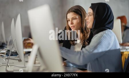 Verschiedene multiethnische Gruppen von weiblichen und männlichen Schülern sitzen im College Room und arbeiten an Schulprojekten am Computer zusammen. Junge Wissenschaftler lernen, sprechen, wenden akademische Fähigkeiten und Wissen im Unterricht an. Stockfoto