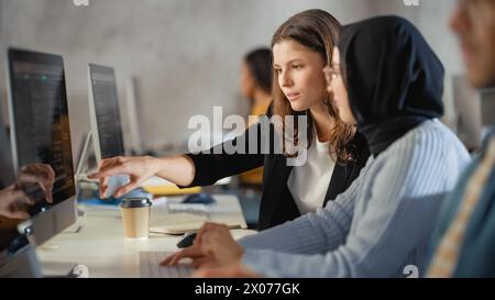 Verschiedene multiethnische Gruppen von weiblichen und männlichen Schülern sitzen im College Room und arbeiten an Schulprojekten am Computer zusammen. Junge Wissenschaftler lernen, sprechen, wenden akademische Fähigkeiten und Wissen im Unterricht an. Stockfoto