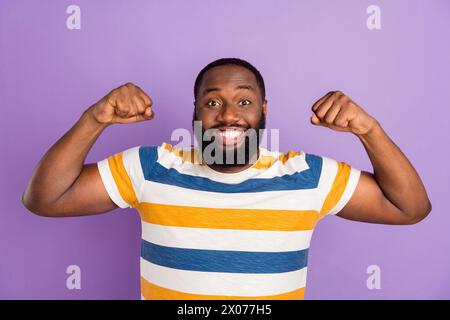 Foto-Porträt des gutaussehenden jungen Mannes zeigen Muskeln, die gekleidetes stilvolles gestreiftes Kleid auf lila Hintergrund isoliert Stockfoto