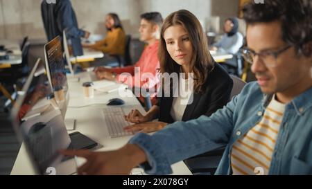 Verschiedene multiethnische Gruppen von weiblichen und männlichen Schülern sitzen im College Room und arbeiten an Schulprojekten am Computer zusammen. Junge Wissenschaftler lernen, sprechen, wenden akademische Fähigkeiten und Wissen im Unterricht an. Stockfoto