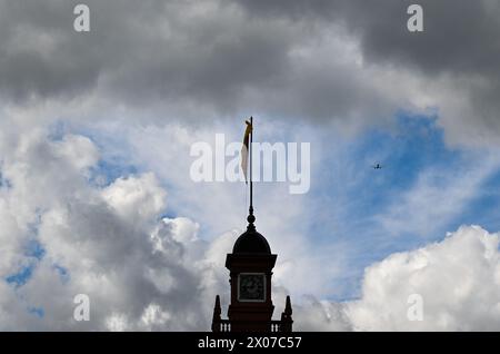 Hanau, Deutschland. April 2024. Über Schloss Philippsruhe im Stadtteil Kesselstadt nähert sich ein Flugzeug am bewölkten Himmel dem Frankfurter Flughafen an. Das barocke Schloss wurde zwischen 1700 und 1725 von Graf Phlipp Reinhard von Hanau erbaut. Vermerk: Arne Dedert/dpa/Alamy Live News Stockfoto