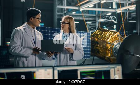 Ingenieur und Techniker, die an der Satellitenkonstruktion arbeiten. Luft- und Raumfahrtbehörde: Ein Team von Wissenschaftlern, die technologische Ausrüstung und Laptop-Computer nutzen, um Raumfahrzeuge für die Weltraumforschung zu entwickeln. Stockfoto