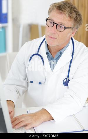 Reifer männlicher Arzt, der seinen Computer benutzt Stockfoto