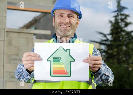 Glücklicher Elektriker mit einer Energieeffizienzkarte Stockfoto