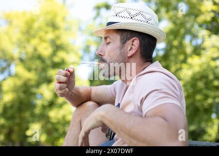 Porträt des Zigarettenrauchenden jungen Mannes im Sommerpark Stockfoto