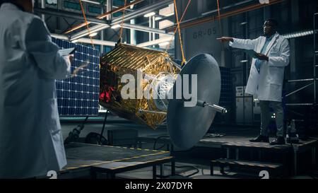 Ingenieur und Techniker, die an der Satellitenkonstruktion arbeiten. Luft- und Raumfahrtbehörde: Ein Team von Wissenschaftlern, das technologische Ausrüstung und Tablet-Computer zur Entwicklung von Raumfahrzeugen für die Weltraumforschung nutzt. Stockfoto