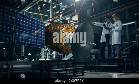 Ingenieur und Techniker, die an der Satellitenkonstruktion arbeiten. Luft- und Raumfahrtbehörde: Ein Team von Wissenschaftlern, die technologische Ausrüstung und Laptop-Computer nutzen, um Raumfahrzeuge für die Weltraumforschung zu entwickeln. Stockfoto