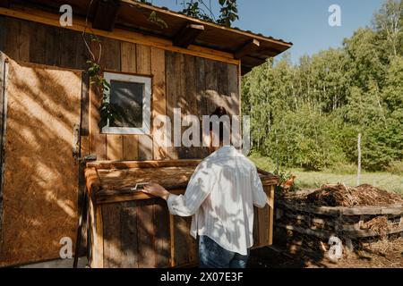 Morgens auf der Farm schaut die Frau in den Hühnerstall, um Eier zu sammeln Stockfoto